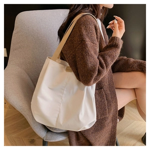 Detail of white canvas tote bag with beige leather handles and vertical stitching seams