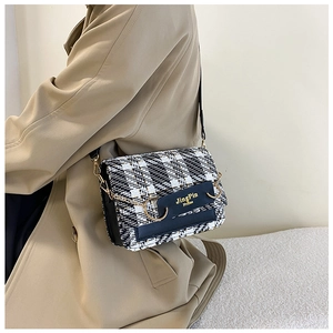 Detailaufnahme von schwarz-weißem Hahnentritt-Tweed mit goldener Trensen-Hardware