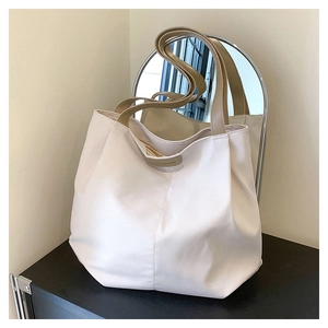Detail of beige canvas tote bag with brown handles and leather Luckybag label