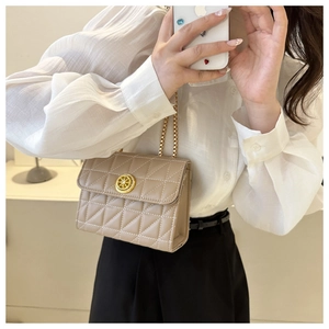 Détail d'un sac à bandoulière matelassé beige avec fermoir doré et bandoulière chaîne