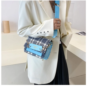 Umhängetasche aus blau-weißem Tweed mit Goldkette und breitem Gurt am Modell getragen