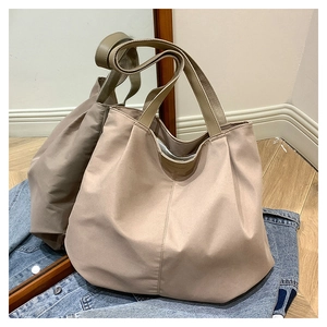 Detail of a large apricot canvas tote bag featuring brown faux leather handles for daily use