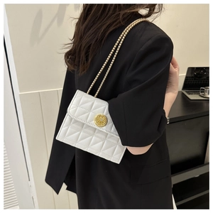 Gros plan d'un sac à bandoulière matelassé blanc avec chaîne dorée et fermoir rond