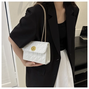 Sac bandoulière matelassé blanc avec boucle dorée porté avec un blazer pour un look chic