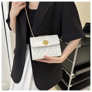 Détail du sac matelassé blanc avec fermoir doré porté sur un blazer noir chic