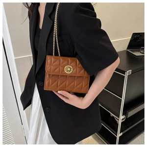Détail d'un sac bandoulière matelassé marron avec un ornement de gouvernail doré élégant