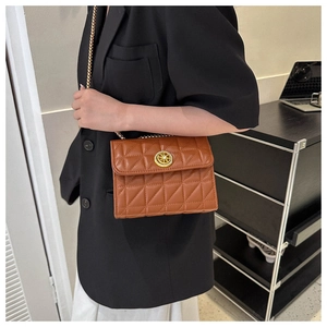 Sac à bandoulière matelassé marron avec chaîne dorée porté par un mannequin en intérieur