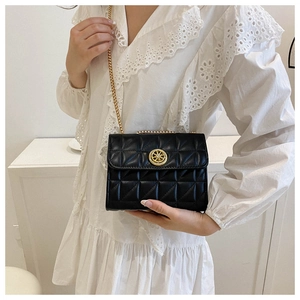 Détail du sac à bandoulière noir matelassé avec boucle dorée sur une chemise en dentelle