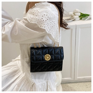 Détail du sac matelassé noir avec boucle dorée circulaire élégante et texture rayons de soleil