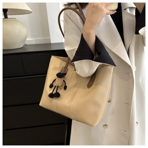 Detail of minimalist beige tote bag with brown straps and cute sheep plush charm