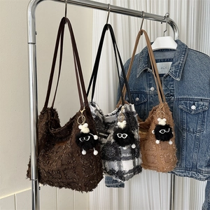 Trois sacs seaux à franges assortis en marron et à carreaux sur un portant