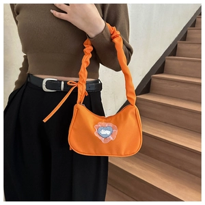 Détail du sac croissant orange avec patch coeur et bandoulière à volants