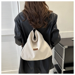Detail view of cream canvas hobo bag with adjustable strap shown on model in leather jacket