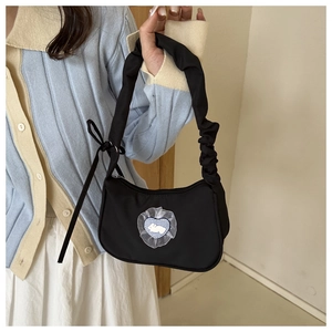 Détail du sac bandoulière noir avec bandoulière plissée et patch cœur lapin