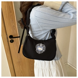Detail of black crescent shoulder bag featuring heart lace patch and ruffled strap