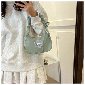 Détail du sac sous l'aisselle vert clair avec anse plissée et patch lapin cœur