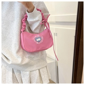 Détail du sac sous le bras rose avec anse froncée et écusson lapin en forme de cœur