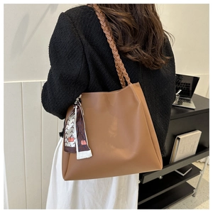Brown tote bag with thick braided strap and silk scarf accessory shown on model back