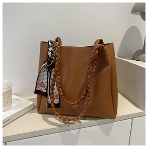 Brown tote bag detail with woven handles and decorative scarf in home office setting