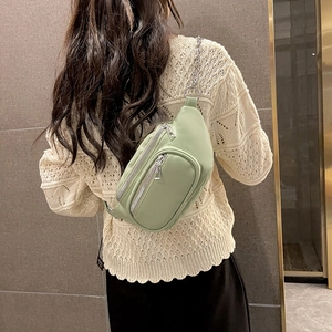 Marsupio alla moda in pelle verde chiaro con catena d'argento indossato su un maglione bianco