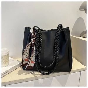 Detail of matte black tote bag featuring a thick braided handle and decorative silk scarf