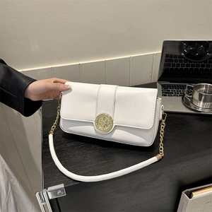 Elegant white crossbody chain bag with round gold metal logo on black studio desk