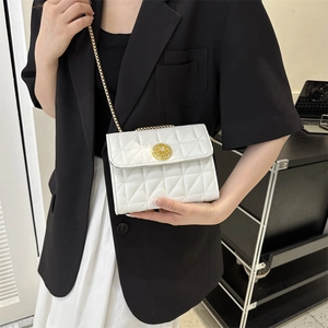 Petit sac carré blanc matelassé avec bandoulière chaîne dorée porté par un mannequin