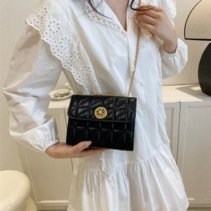 Sac bandoulière noir matelassé avec chaîne dorée présenté dans un décor moderne