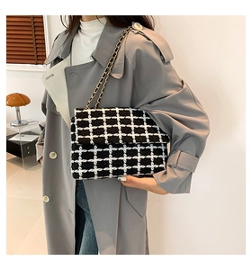 Détail du sac bandoulière en tweed à carreaux avec chaîne en métal et texture tissée