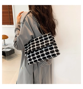 Détail du sac bandoulière en tweed noir et blanc avec bandoulière chaîne dorée à l'épaule