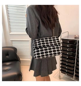 Gros plan du sac bandoulière en tweed à carreaux noir et blanc avec chaîne en métal