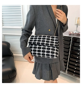 Détail du sac à rabat en tweed à carreaux avec chaîne dorée porté avec un tailleur gris