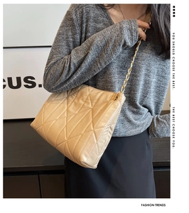 Detail of beige quilted shoulder bag with golden chain strap on a fashion model