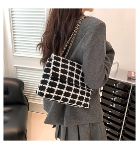 Détail du sac classique en laine à carreaux noir et blanc avec chaîne dorée sur mannequin