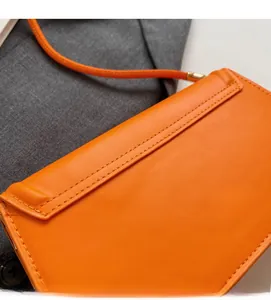Macro detail of the orange leather bag showing fine stitching and premium texture