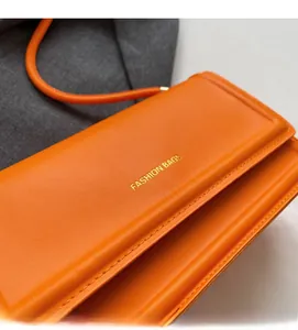 Close-up of orange leather texture and golden Fashion Bags lettering on a shoulder bag
