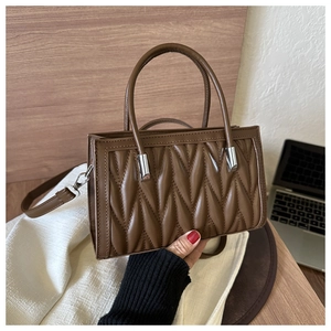 Detail of dark brown quilted handbag showing textured pleats and silver metal hardware