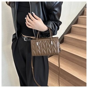 Detail of a brown pleated PU leather crossbody bag with vertical wavy pattern texture