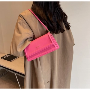 Model wearing a bright pink faux leather shoulder bag with a stylish beige trench coat