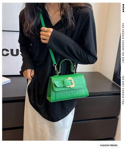 Detail of bright green crocodile embossed shoulder bag with vintage gold buckle on model
