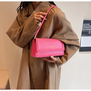 Close-up of pink rectangular shoulder bag with accordion side gussets and gold hardware