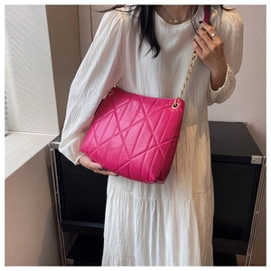 Detail of fuchsia PU leather shoulder bag featuring geometric quilting and gold chain strap