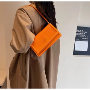 Detail of orange faux leather shoulder bag featuring 'FASHION BAGS' embossed logo