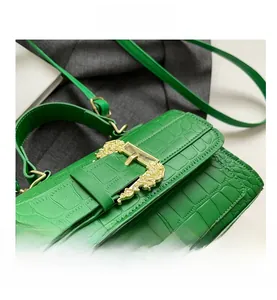 Detail of green faux crocodile skin bag with vintage gold baroque buckle and strap