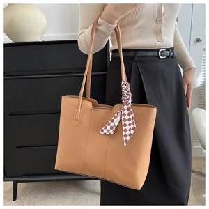 Detail of camel leather tote bag with a decorative red and white checkered silk scarf