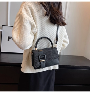 Rear view of a black leather crossbody bag with glitter details worn over a white sweater