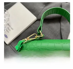 Detail of green croc-embossed bag featuring golden lion head buckle and metal hooks