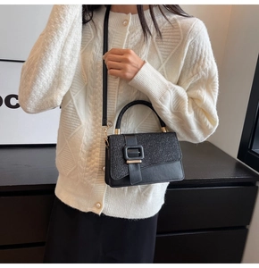 Detail of black crossbody bag with gold-tone buckle and matte textured flap for women