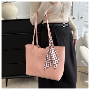 Detail of soft pink PU leather tote bag with stylish checkerboard ribbon on shoulder strap