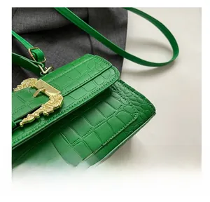 Detailed macro view of vibrant green crocodile-textured leather with golden metal buckle